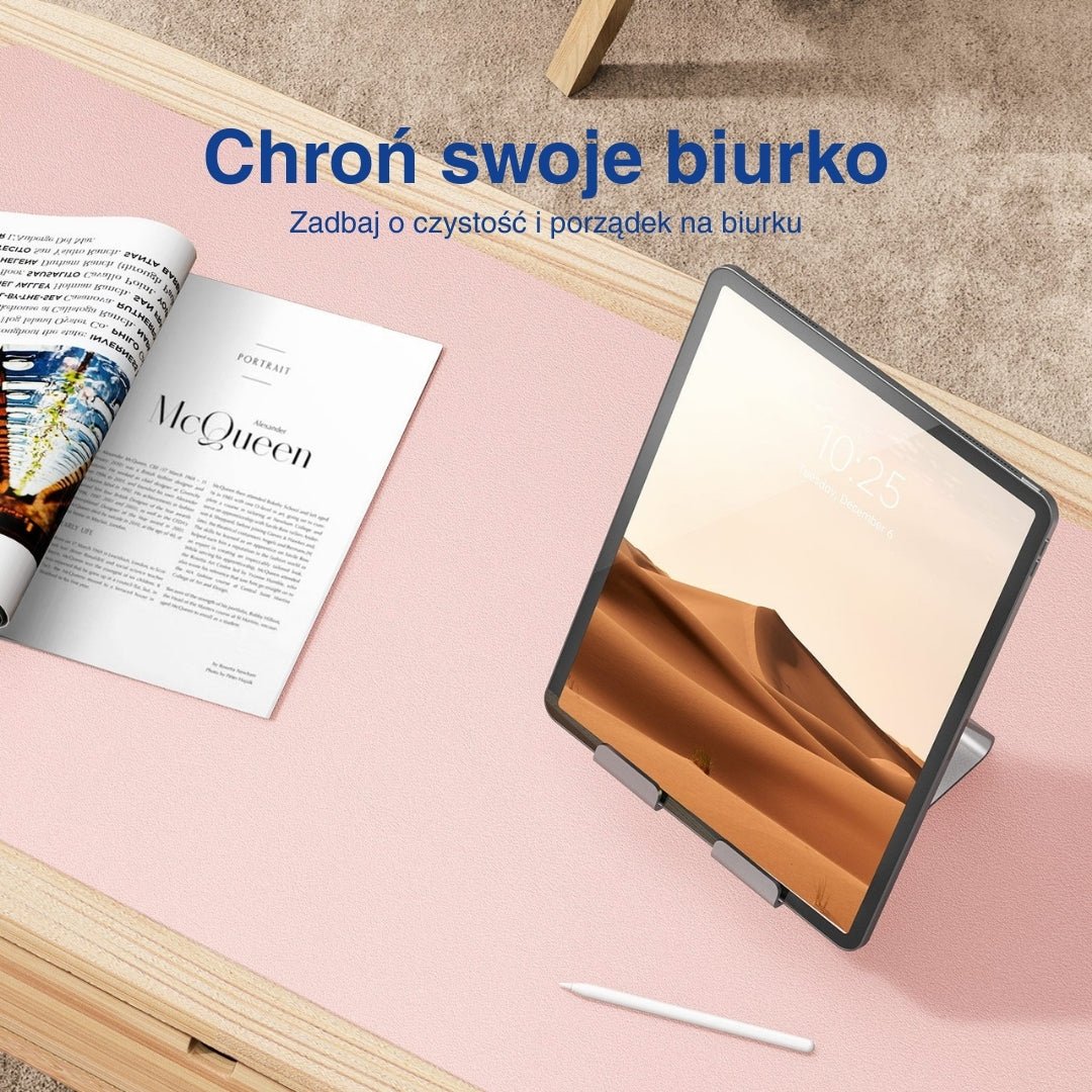 Różowa mata na biurko z tabletem i magazynem na drewnianym stole.