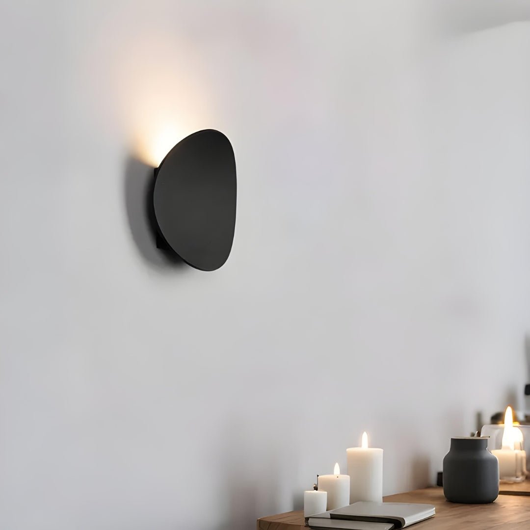 Czarna metalowa lampa łazienkowa nad stołem z trzema świecami