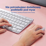 Zbliżenie dłoni na białej klawiaturze i myszy na białej macie na biurko.